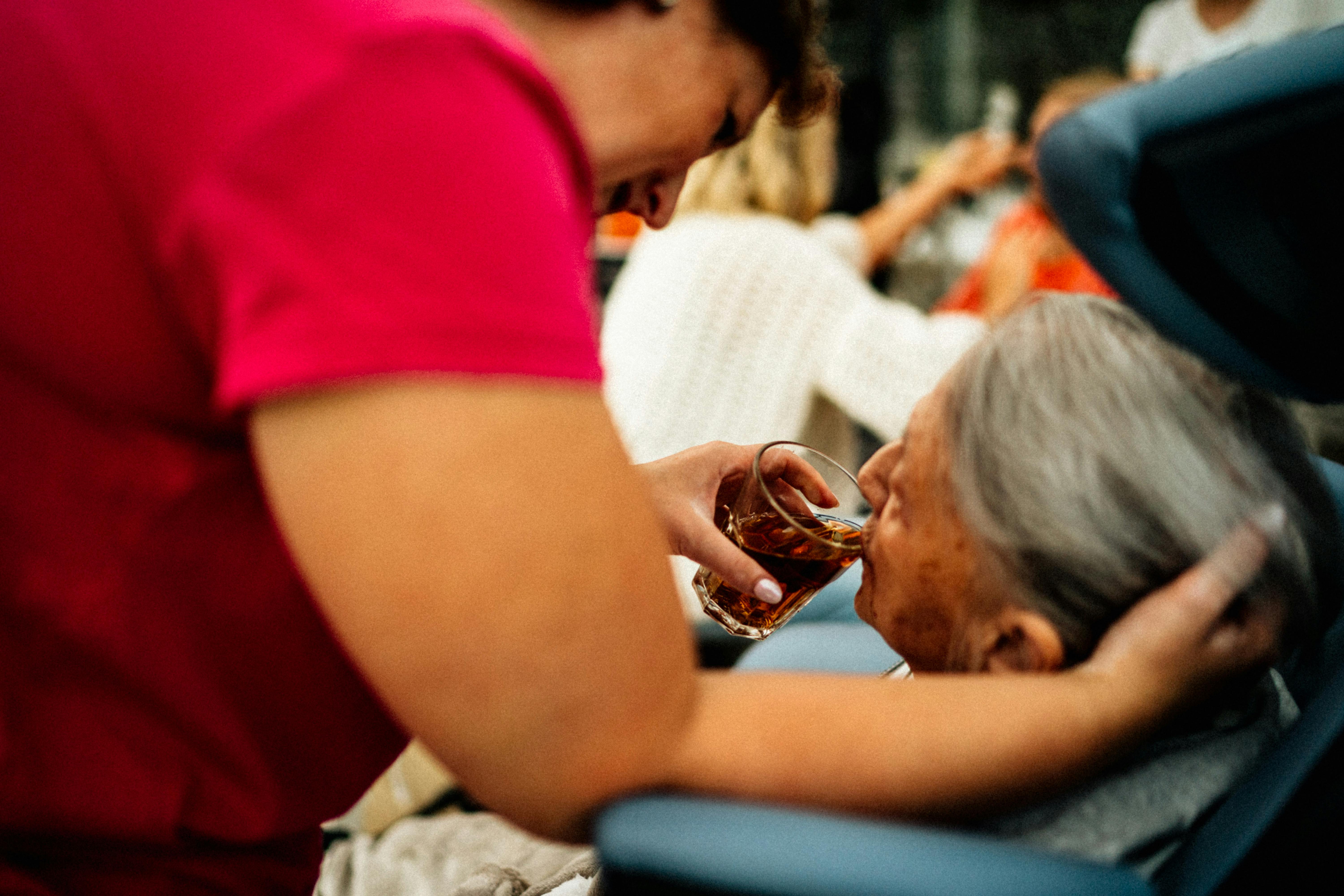 Carer supporting an older client with a drink